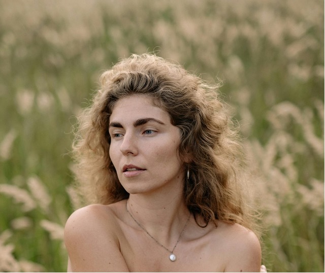 Woman with curly, voluminous hair in a field, cover image for an article about hair loss in menopause